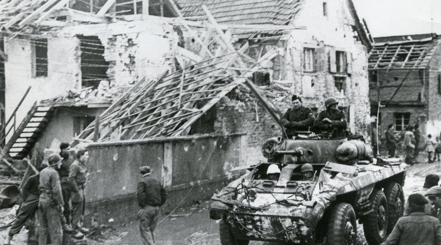 Des soldats américains sur un char traversant Sélestat  dont plusieurs quartiers sont en ruines. 