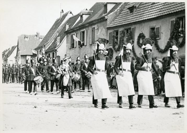 Sapeurs, suivis de tambour-major, clique, Colonel, Drapeau, Cantinière et voltigeurs du 69e régiment d'Infanterie (époque : 1867). 