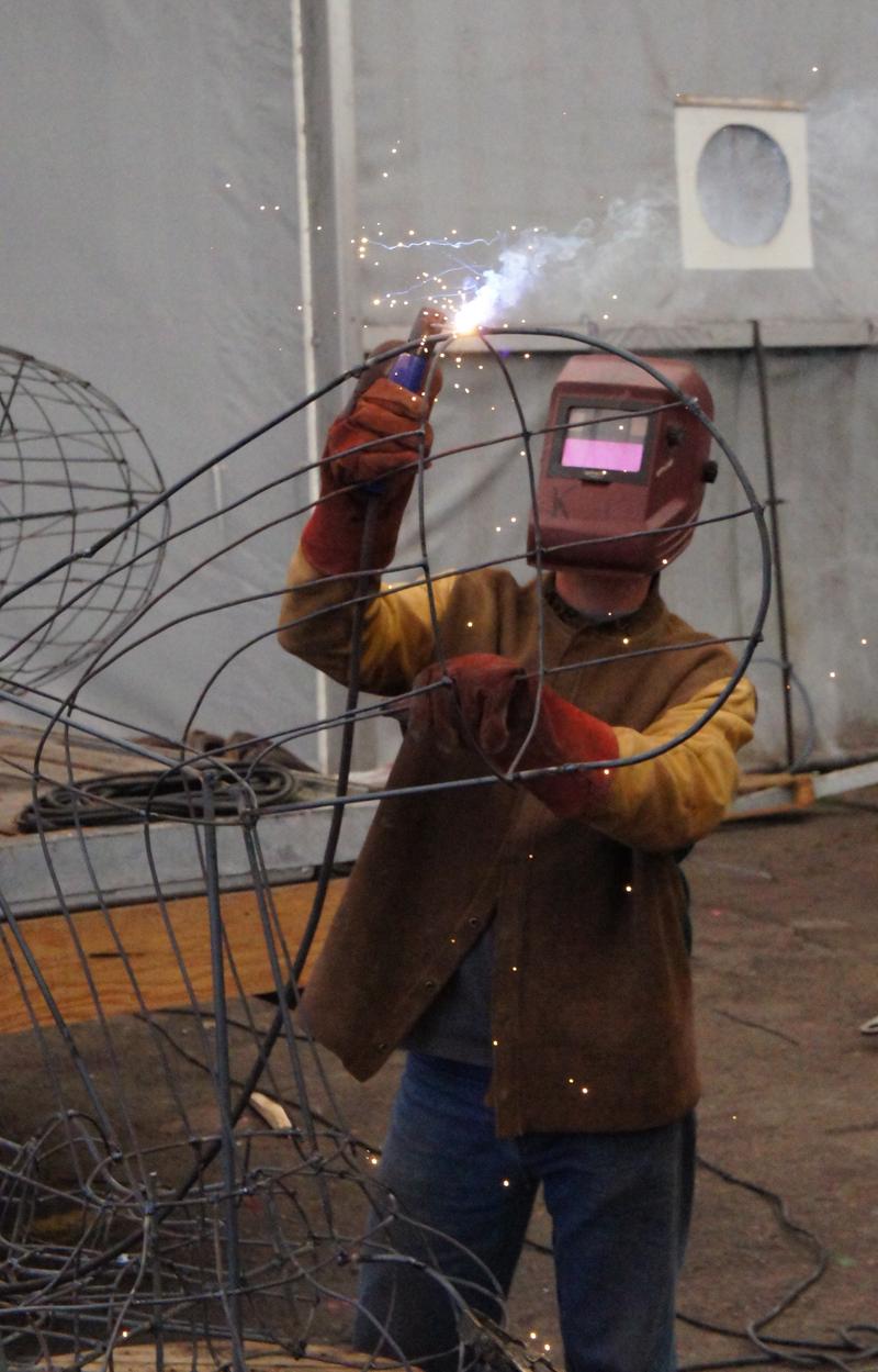 cette photo présente un ouvrier municipal en train de souder la structure métallique d'un char